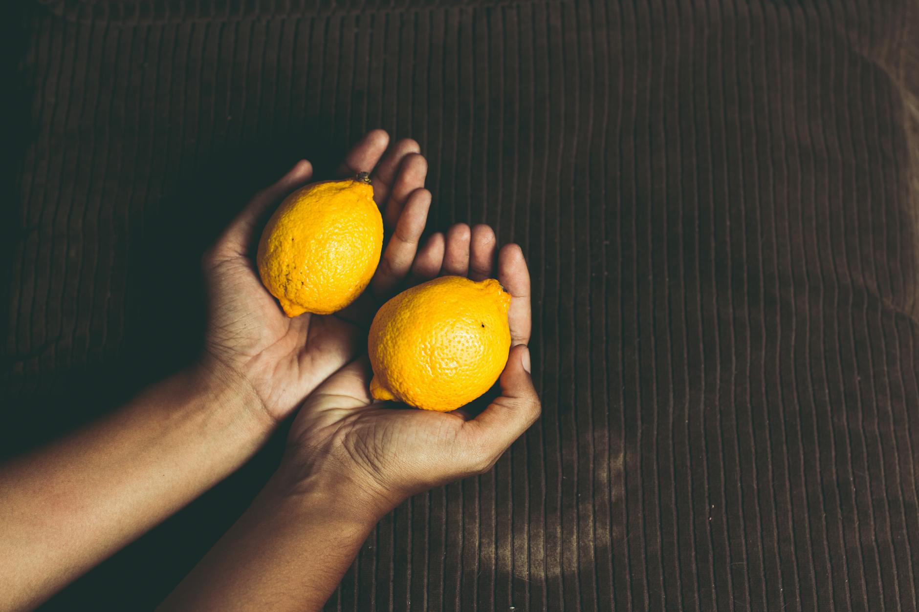 Close-up of a hand holding an orange vibrator against a purple background, symbolizing careful, intentional touch.