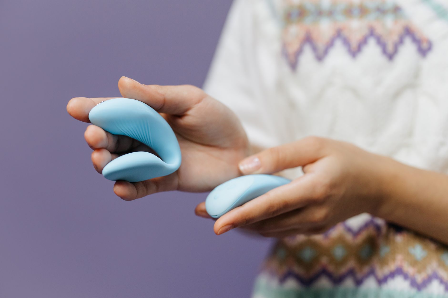 Intimate close-up of hands holding a sleek lemon vibrator together, showing couple connection and shared pleasure