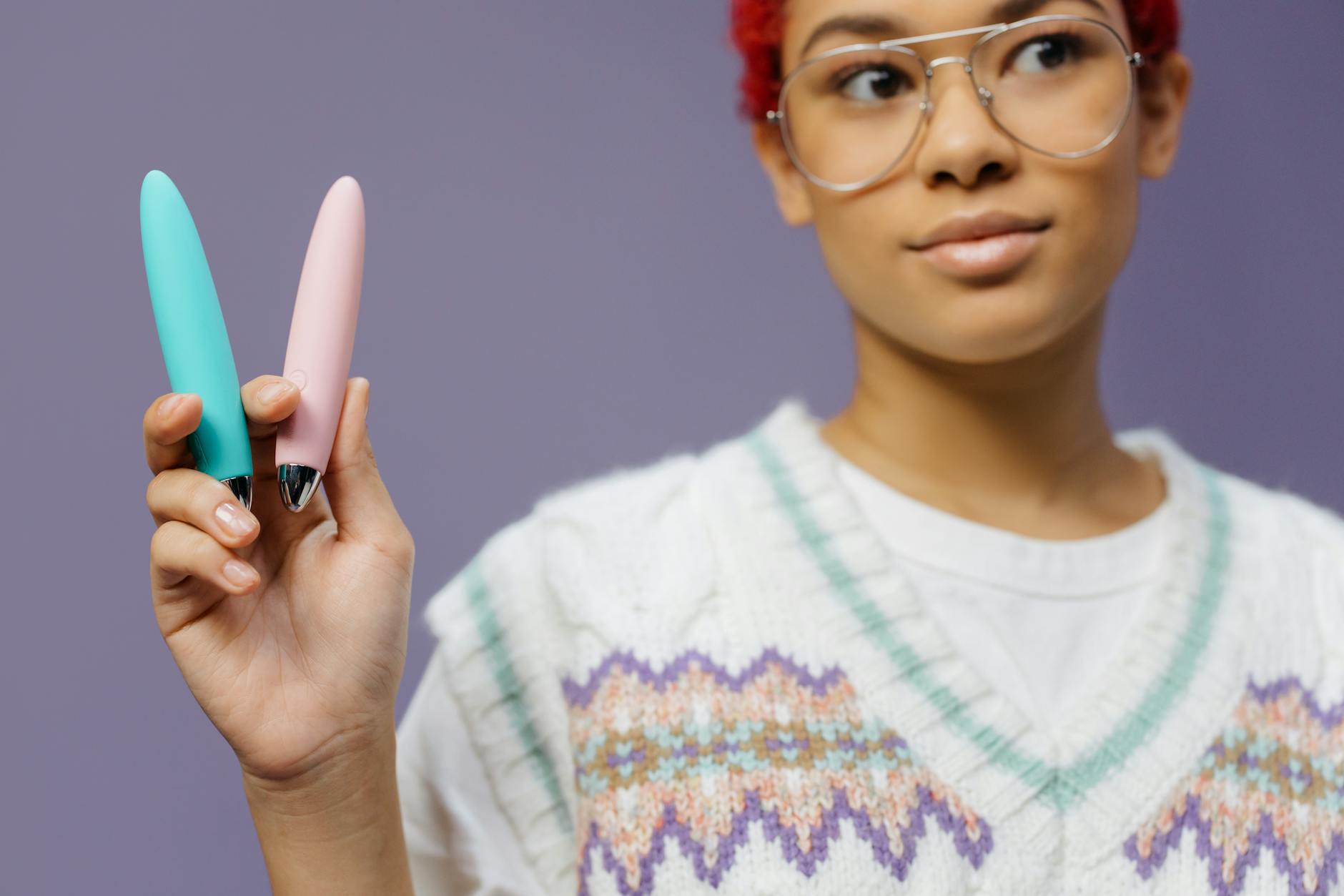 Woman holding two vibrators, representing options for partnered pleasure