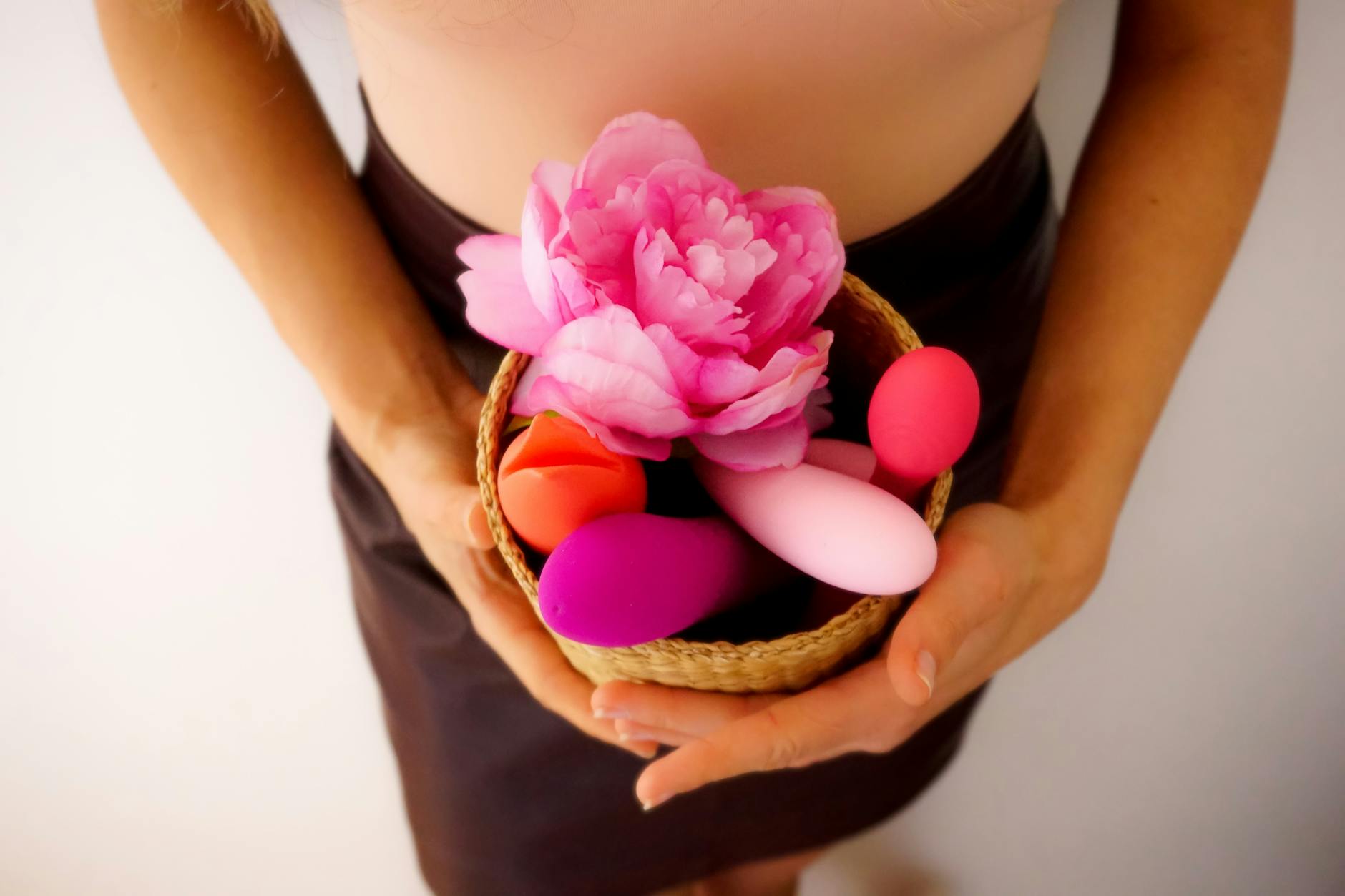 A woman contemplatively holding blue and pink silicone vibrators