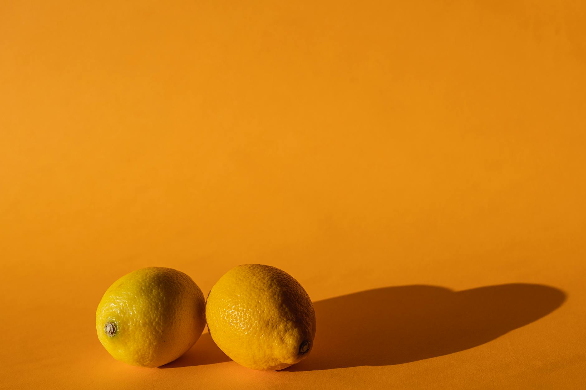 Fresh lemons on a bright yellow background, symbolizing the focused intensity of pleasure
